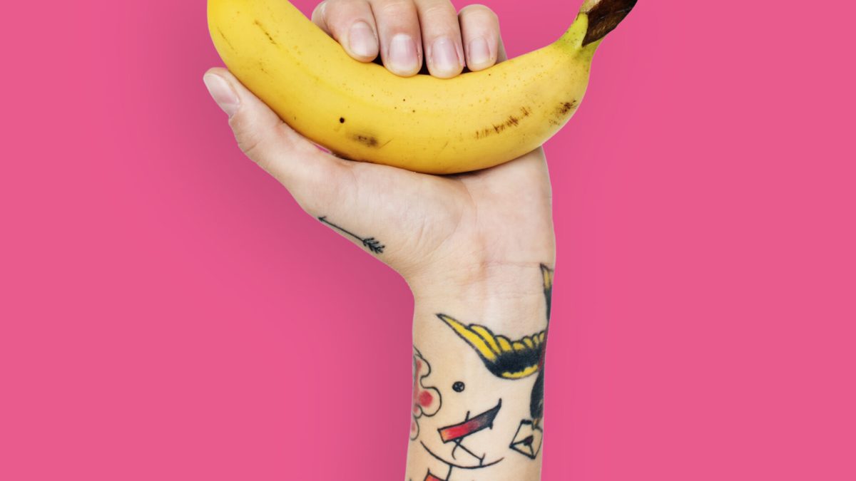 Tattooed hand holding a banana